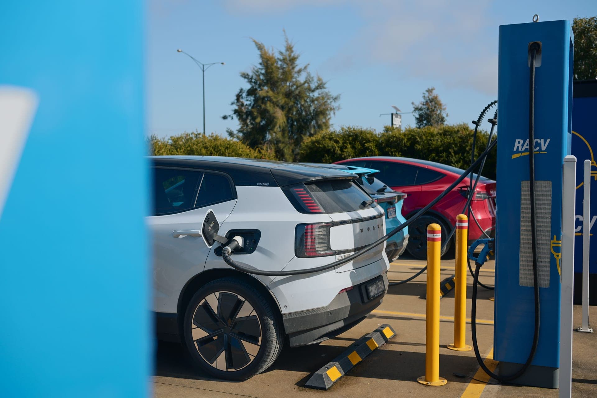 A white electric car plugged in at a public charging post