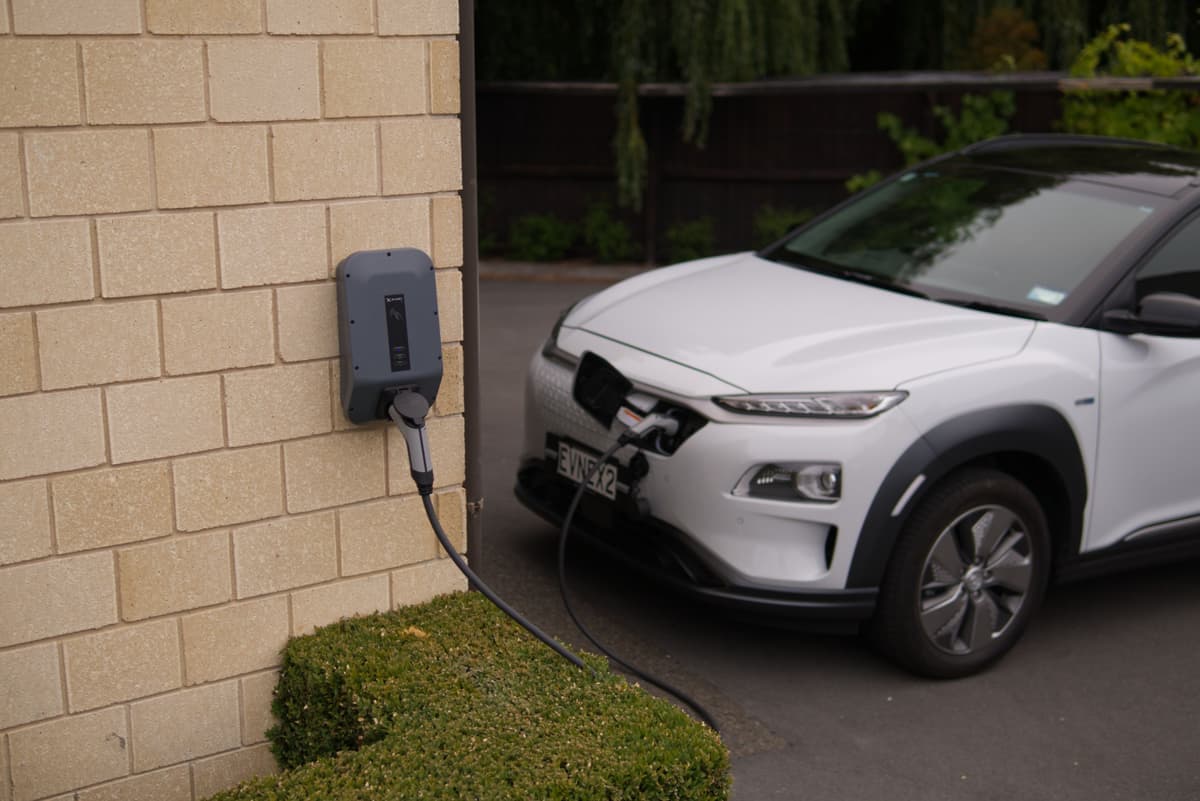 An electric car charging on a driveway outside a house