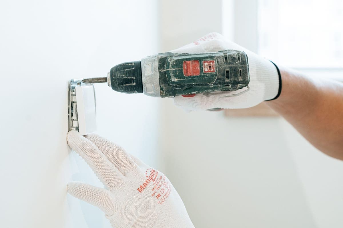 An electrician working on a wall-mounted electrical installation