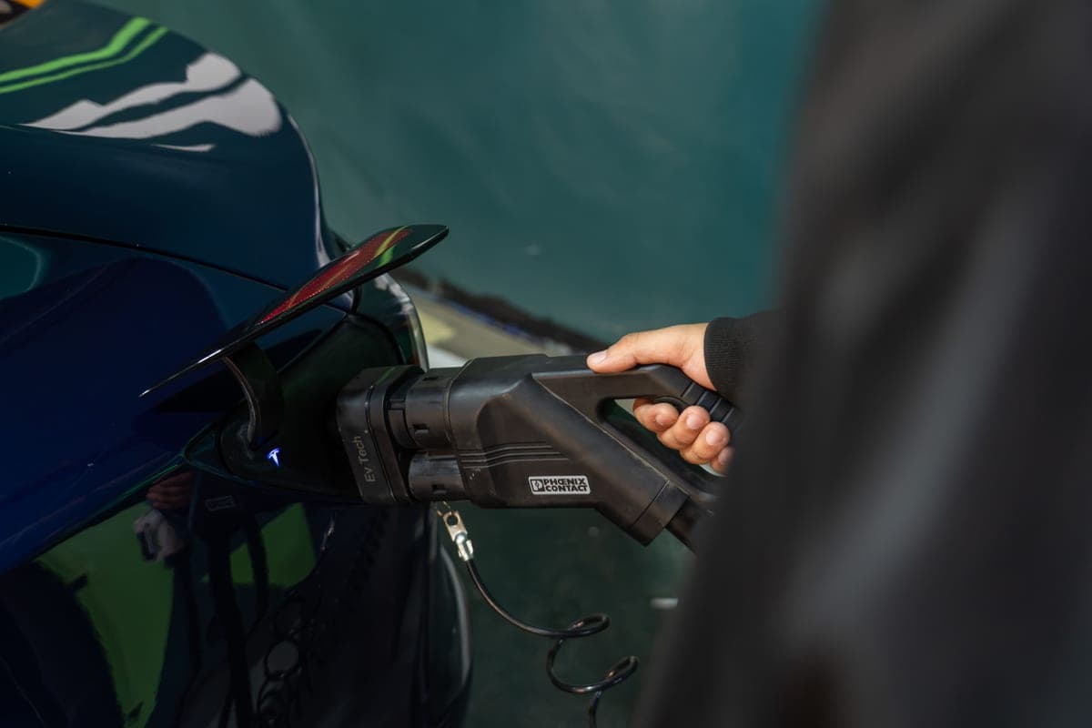 A person connecting a charging cable to an electric car at home