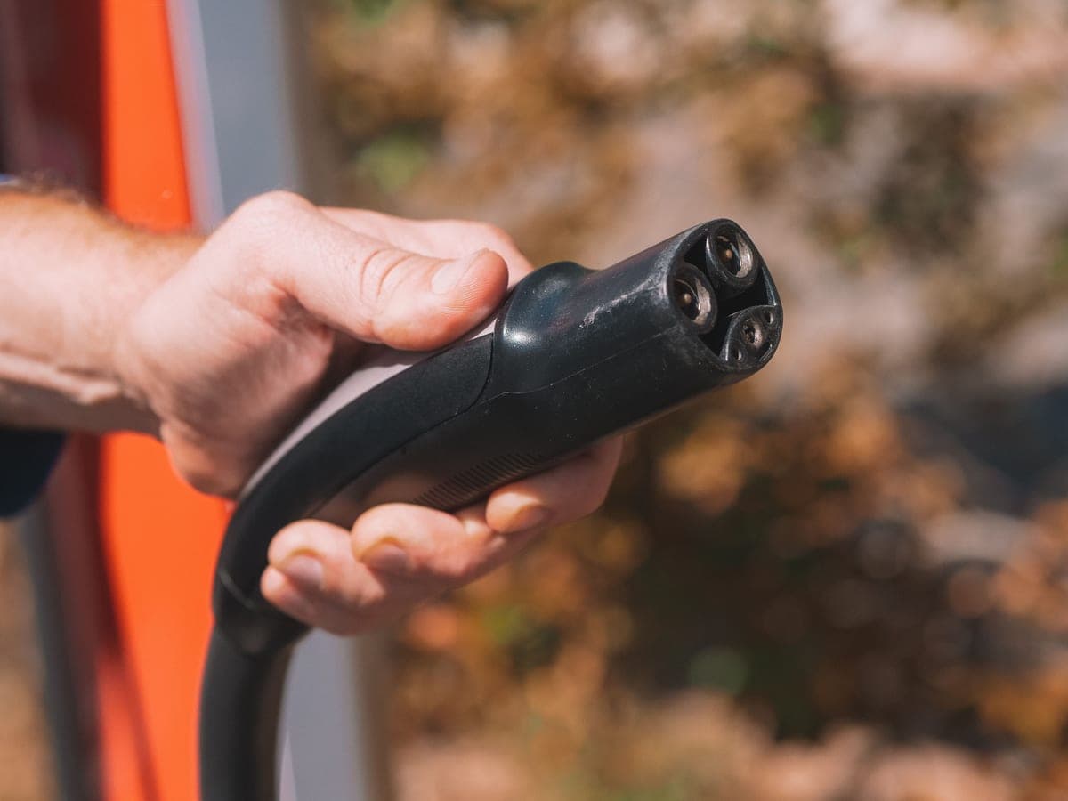 A person holding an electric vehicle charging connector