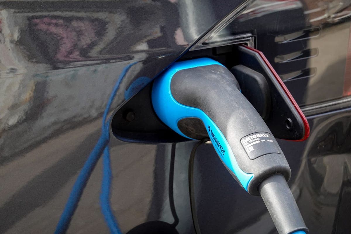 A hand holding an electric vehicle charging adapter and connector