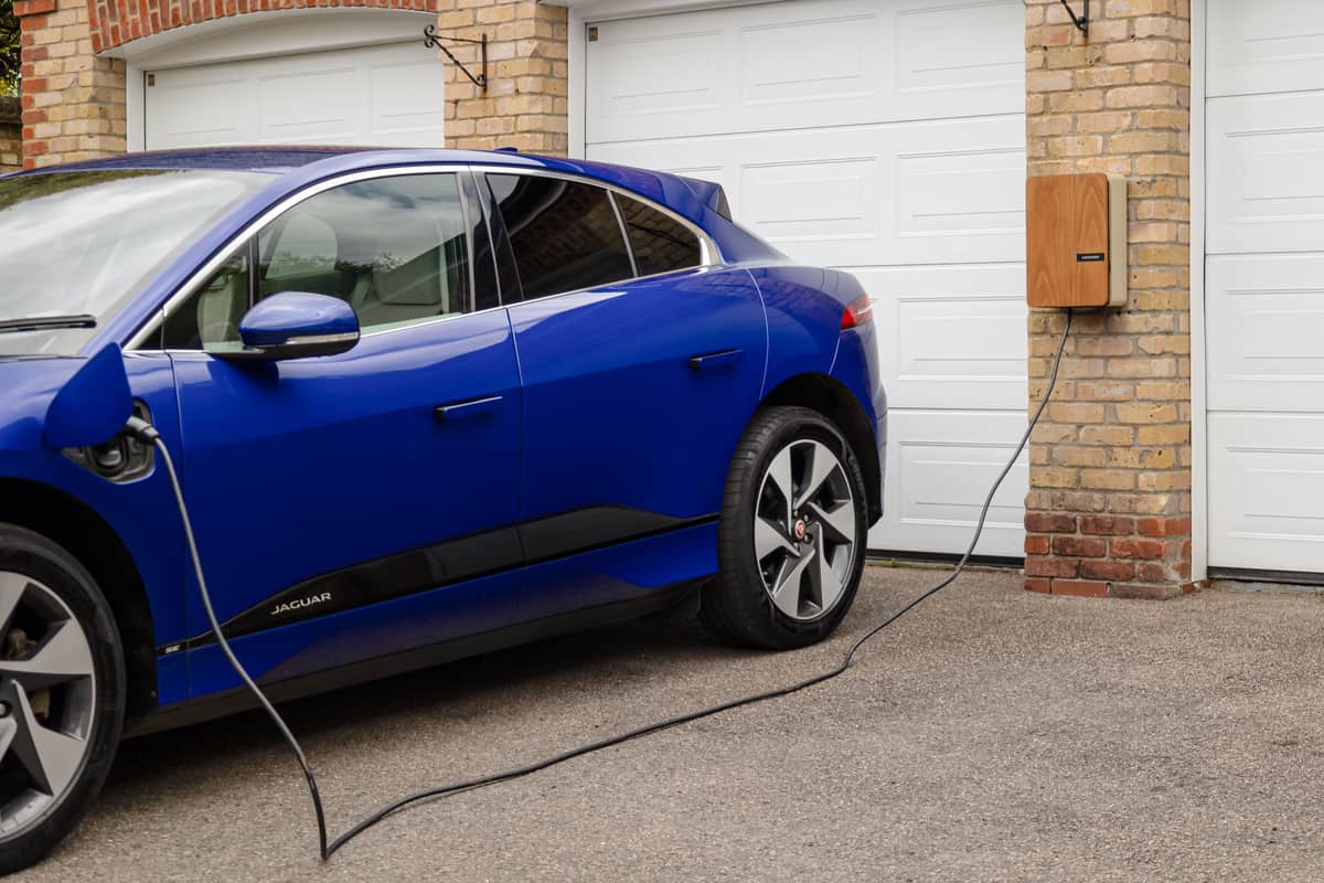 An electric car charging on a driveway outside a house