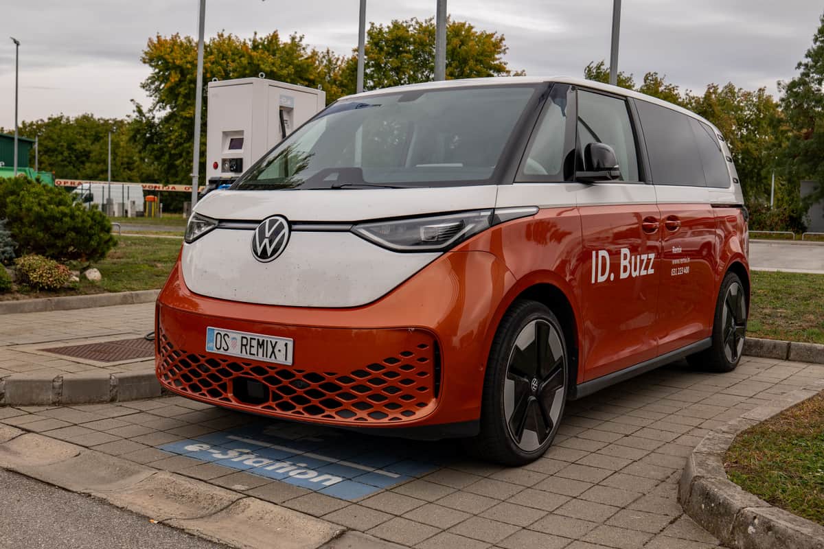 An orange and white Volkswagen ID. Buzz parked at a public charging bay