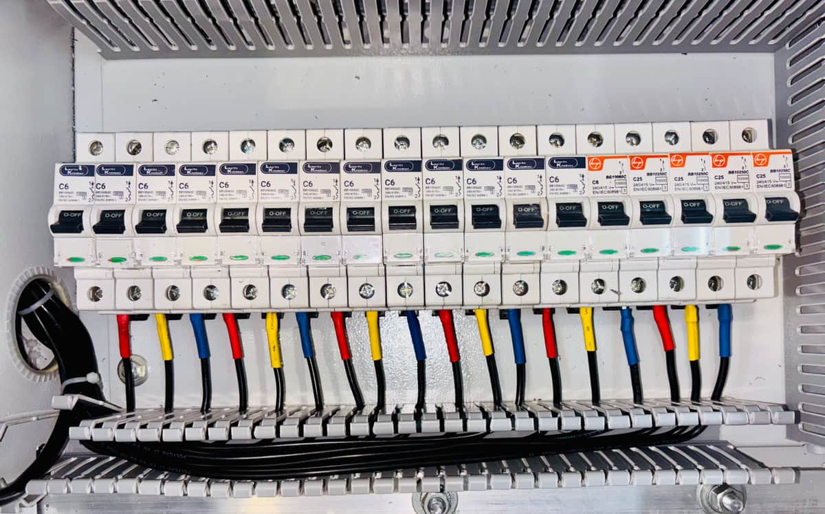 Rows of circuit breakers and colored wiring inside an open electrical enclosure