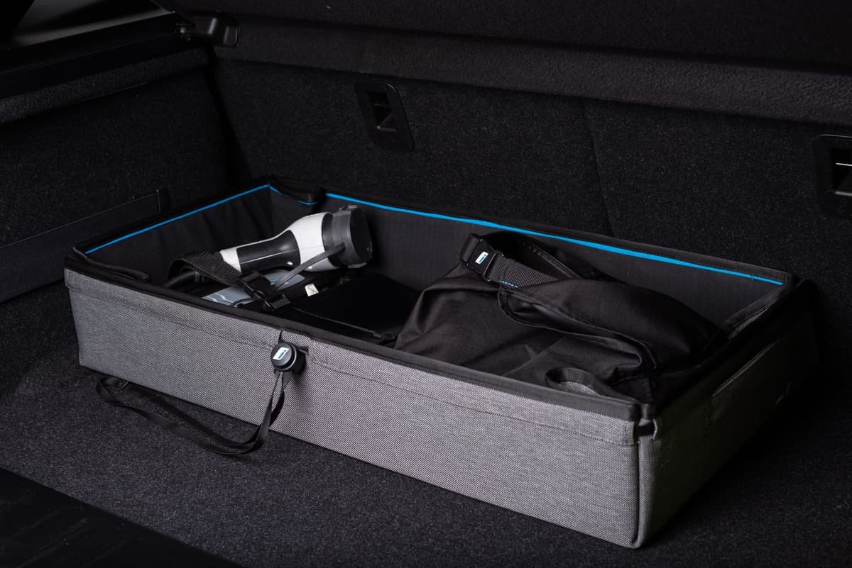 A portable EV charger and cable stored in a car trunk organizer